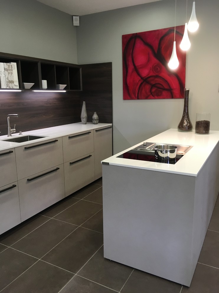 Small modern galley eat-in kitchen in Le Havre with an integrated sink, flat-panel cabinets, beige cabinets, quartzite benchtops, timber splashback, stainless steel appliances, ceramic floors, with island, brown floor and white benchtop.