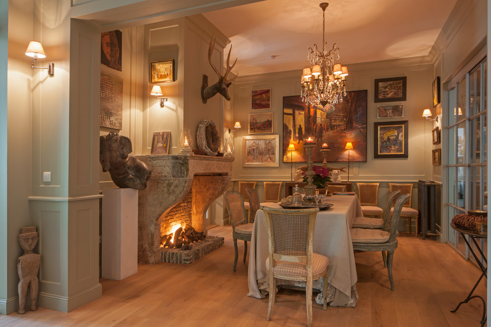 This is an example of a mid-sized country separate dining room in Hamburg with light hardwood floors, beige walls, a standard fireplace and a stone fireplace surround.