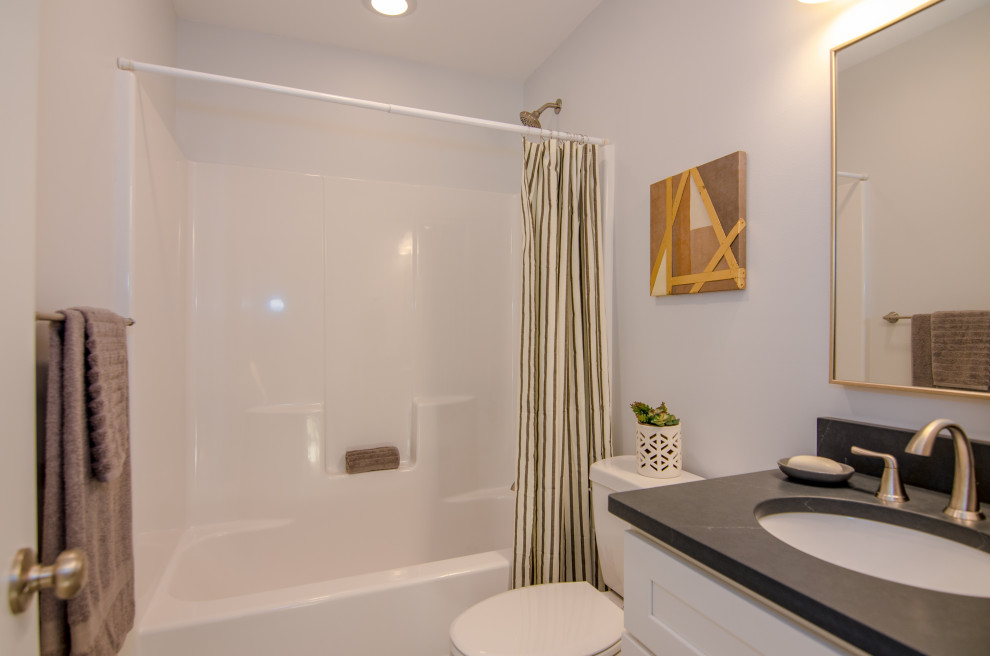This is an example of a mid-sized traditional kids bathroom in Other with shaker cabinets, white cabinets, an alcove tub, a shower/bathtub combo, a two-piece toilet, blue walls, ceramic floors, an undermount sink, granite benchtops, a shower curtain, black benchtops, a single vanity and a built-in vanity.