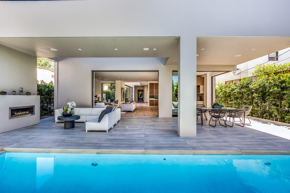 Inspiration for a large modern backyard rectangular lap pool in Los Angeles with a water feature and tile.