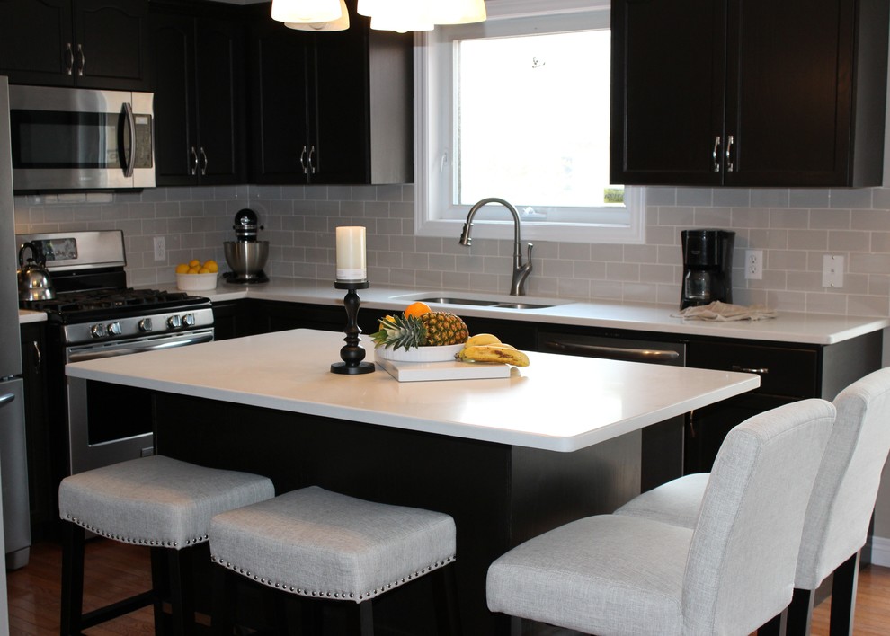 Example of a mid-sized transitional u-shaped medium tone wood floor open concept kitchen design in Toronto with an undermount sink, recessed-panel cabinets, dark wood cabinets, quartzite countertops, gray backsplash, subway tile backsplash, stainless steel appliances and an island