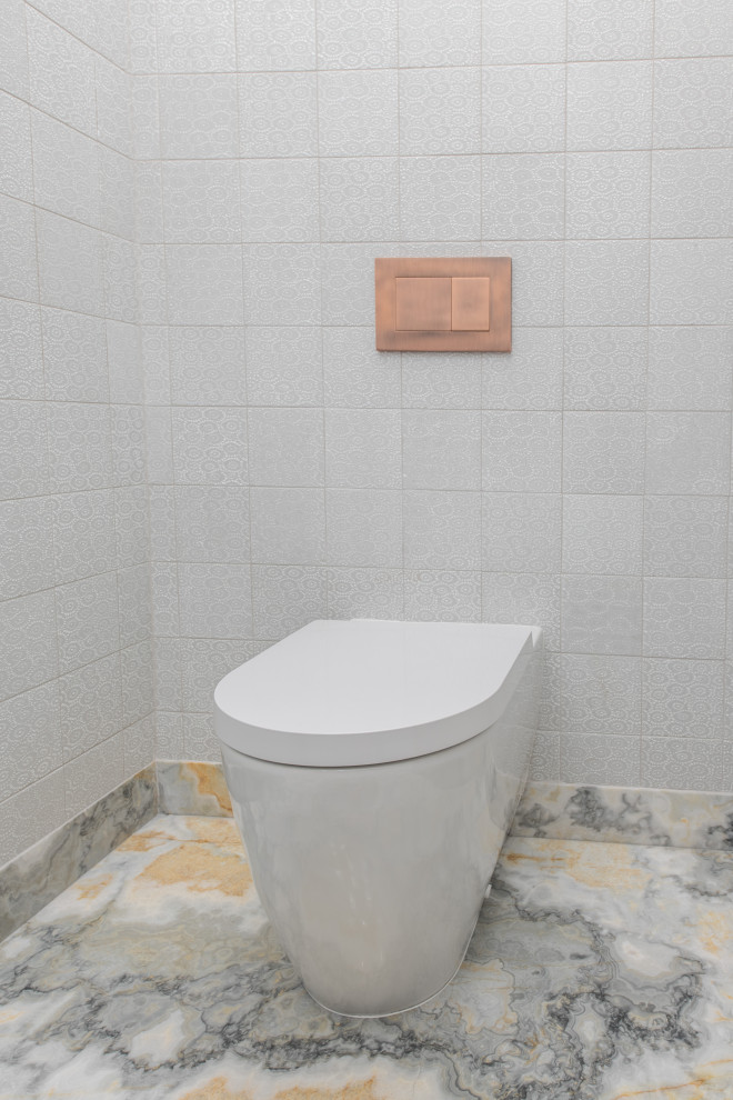 Cette photo montre un WC suspendu tendance de taille moyenne avec un placard à porte plane, des portes de placard grises, un carrelage blanc, des carreaux de céramique, un mur blanc, une vasque, un plan de toilette en onyx, un sol gris, un plan de toilette gris et meuble-lavabo suspendu.