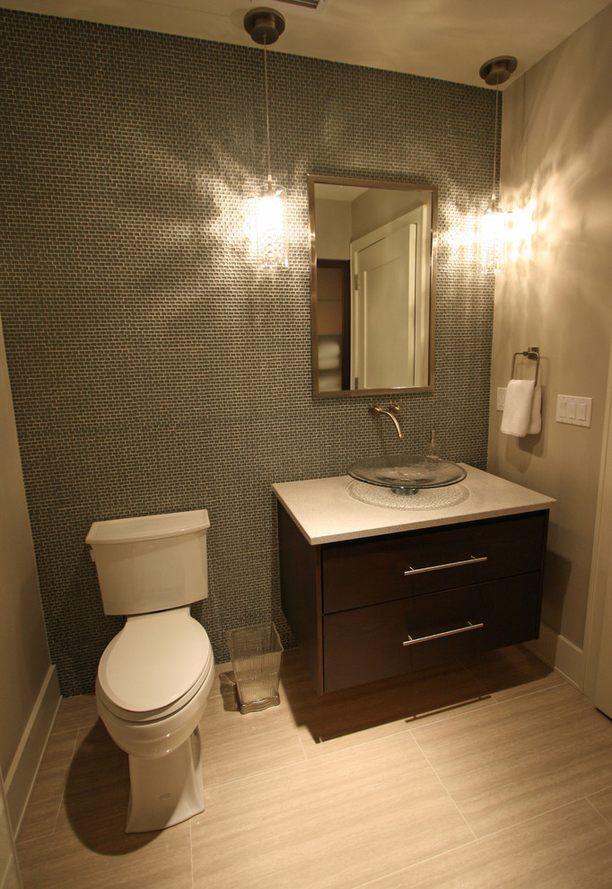 Photo of a mid-sized contemporary powder room in Seattle with a vessel sink, furniture-like cabinets, dark wood cabinets, engineered quartz benchtops, a two-piece toilet, blue tile, glass tile, grey walls and porcelain floors.