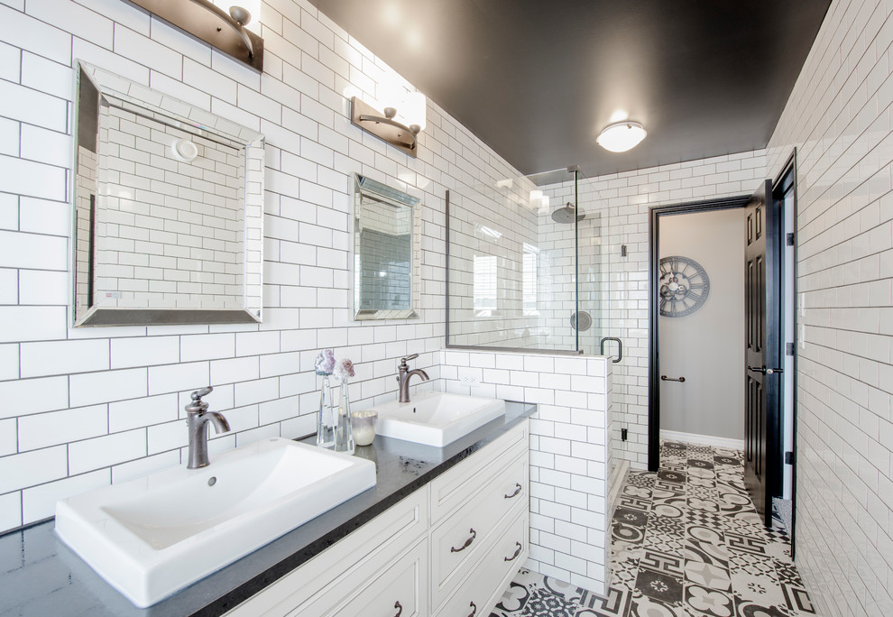 Inspiration for a transitional 3/4 white tile and subway tile multicolored floor corner shower remodel in Edmonton with recessed-panel cabinets, white cabinets, white walls, a vessel sink, a hinged shower door and black countertops