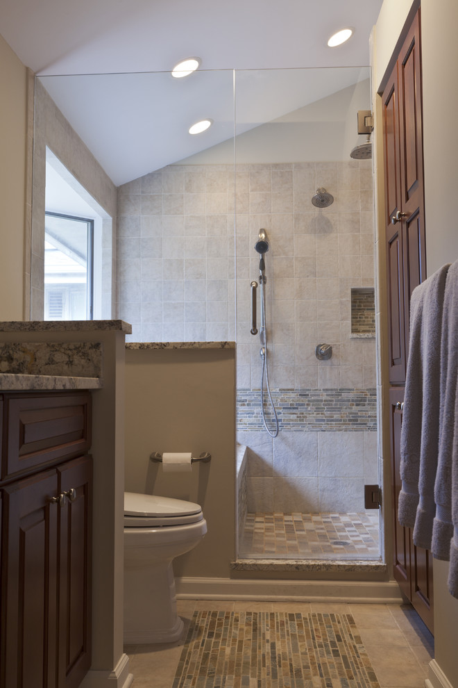 This is an example of a mid-sized country master bathroom in Bridgeport with an undermount sink, raised-panel cabinets, medium wood cabinets, granite benchtops, a drop-in tub, a double shower, a two-piece toilet, multi-coloured tile, stone tile, beige walls and porcelain floors.