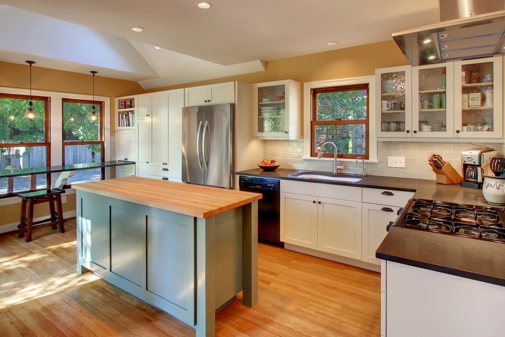 Mid-sized eclectic l-shaped eat-in kitchen in Seattle with an undermount sink, shaker cabinets, yellow cabinets, grey splashback, ceramic splashback, stainless steel appliances, light hardwood floors and multiple islands.