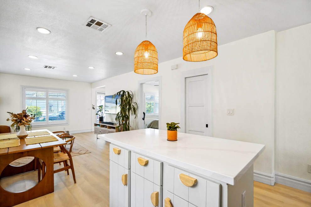 Medium sized farmhouse l-shaped open plan kitchen in Los Angeles with a belfast sink, beaded cabinets, white cabinets, marble worktops, white splashback, ceramic splashback, white appliances, vinyl flooring, an island, beige floors, white worktops and a vaulted ceiling.