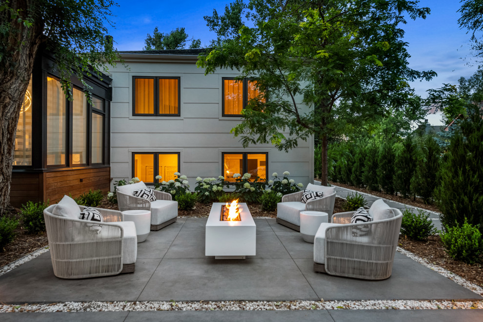 Cette image montre une petite terrasse avant minimaliste avec un foyer extérieur et des pavés en béton.