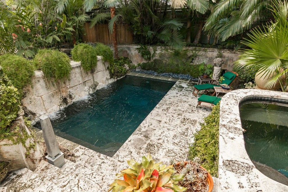 Photo of a mid-sized tropical courtyard rectangular natural pool in Miami with a water feature and natural stone pavers.