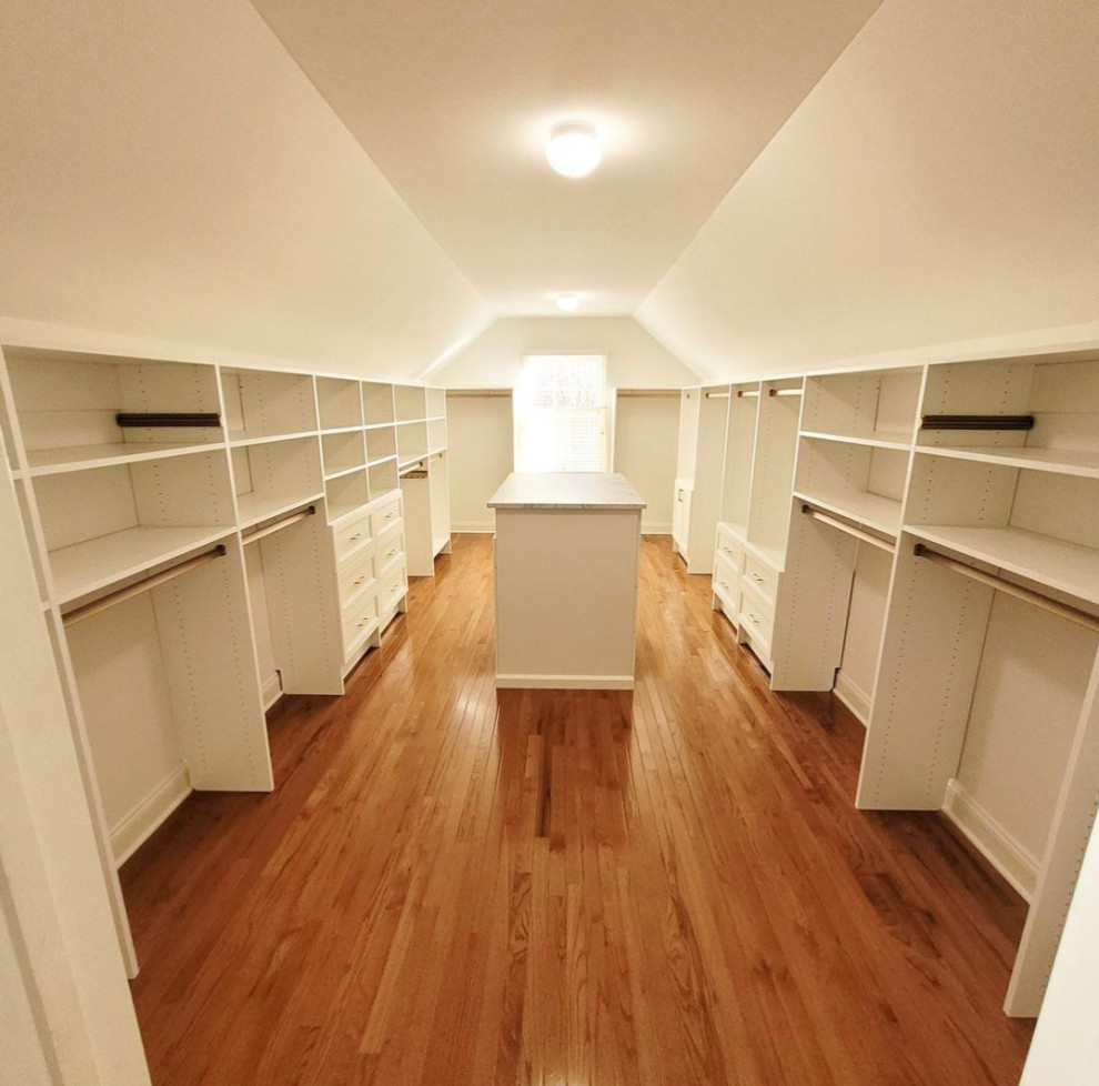 Walk-in closet - large traditional gender-neutral medium tone wood floor, brown floor and vaulted ceiling walk-in closet idea in New York with recessed-panel cabinets and white cabinets
