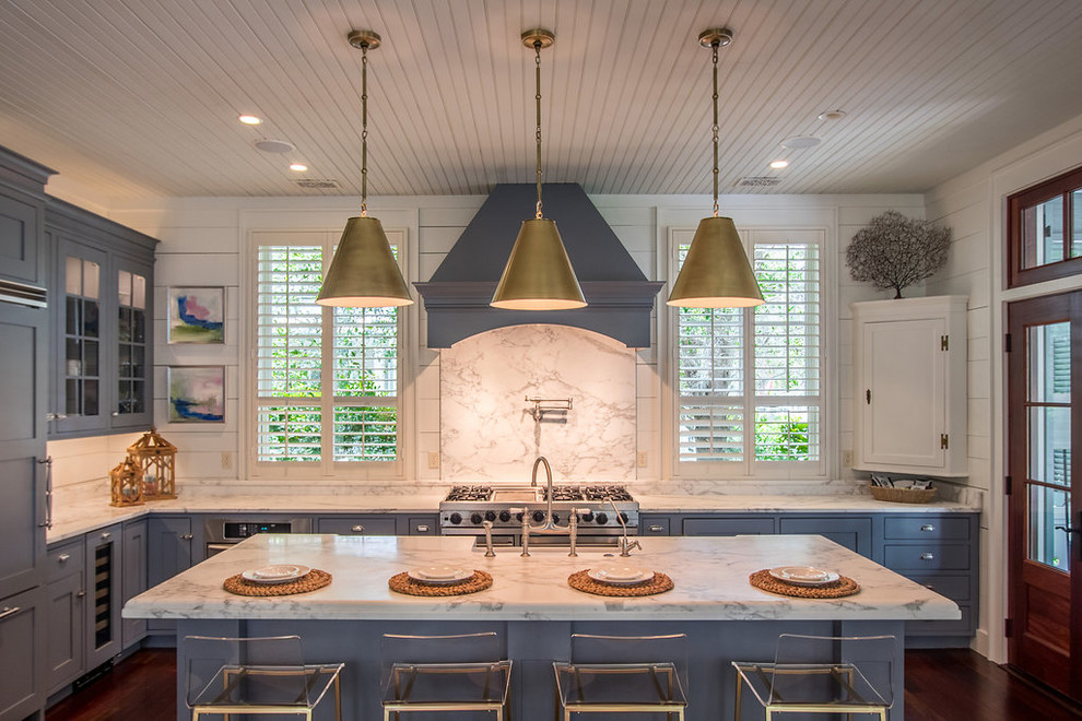 Photo of a beach style kitchen in Atlanta with blue cabinets, marble benchtops, white splashback, marble splashback, stainless steel appliances, dark hardwood floors, with island, white benchtop and beaded inset cabinets.