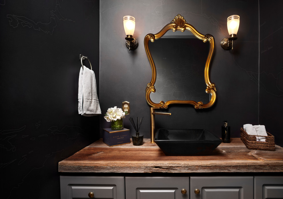 Design ideas for a small transitional powder room in Toronto with a vessel sink, raised-panel cabinets, grey cabinets, wood benchtops, black walls and brown benchtops.