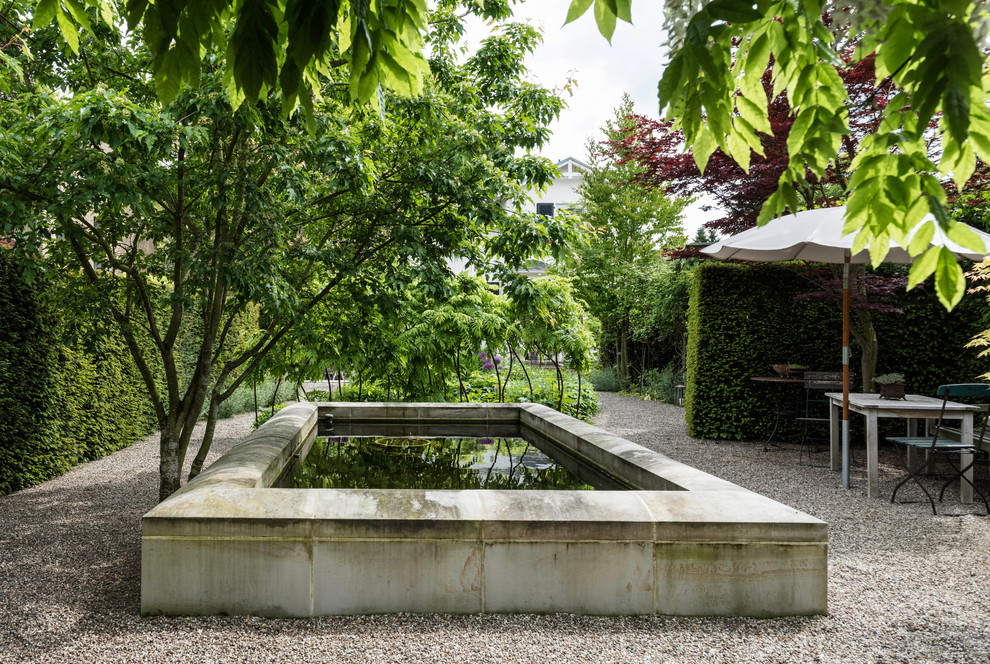 This is an example of a mid-sized mediterranean side yard partial sun garden for summer in Hamburg with a water feature and gravel.