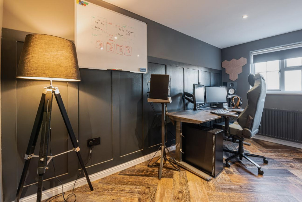 Foto de despacho blanco contemporáneo de tamaño medio con paredes grises, suelo laminado, escritorio independiente, suelo marrón y panelado