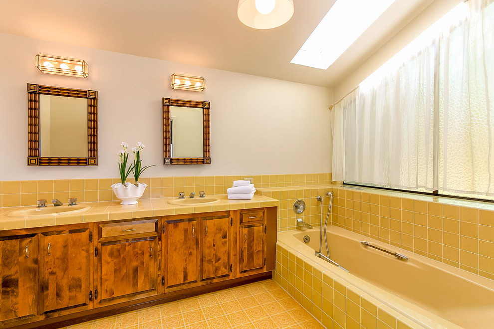 Mid-sized beach style bathroom in Seattle with raised-panel cabinets, medium wood cabinets, a drop-in tub, yellow tile, a drop-in sink, tile benchtops and yellow benchtops.