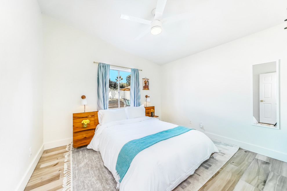 Cette photo montre une chambre d'amis tendance de taille moyenne avec un mur blanc, un sol en contreplaqué, un sol beige et un plafond voûté.