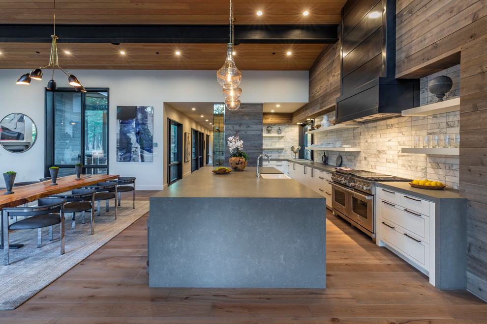 Inspiration for a large modern l-shaped eat-in kitchen in Other with a farmhouse sink, white cabinets, stainless steel appliances, with island, grey benchtop, quartz benchtops, white splashback, marble splashback, light hardwood floors and beige floor.