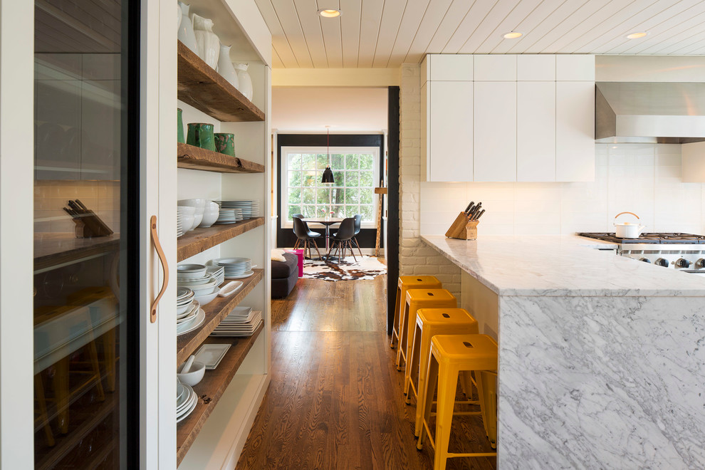 This is an example of a country u-shaped kitchen in Minneapolis with flat-panel cabinets, white cabinets, dark hardwood floors and a peninsula.