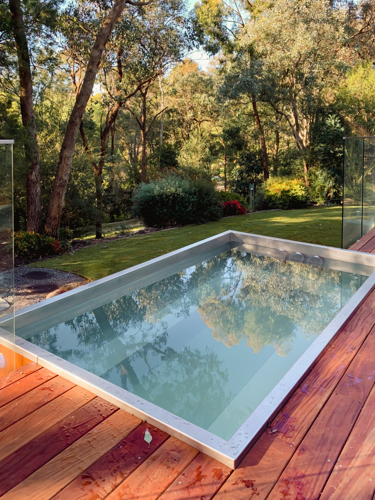 На фото: наземный, прямоугольный бассейн среднего размера на заднем дворе в стиле ретро с джакузи и настилом с