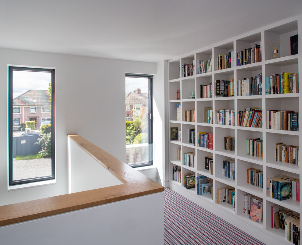 Design ideas for a mid-sized contemporary home office in Dublin with a library, white walls, carpet, a freestanding desk and multi-coloured floor.