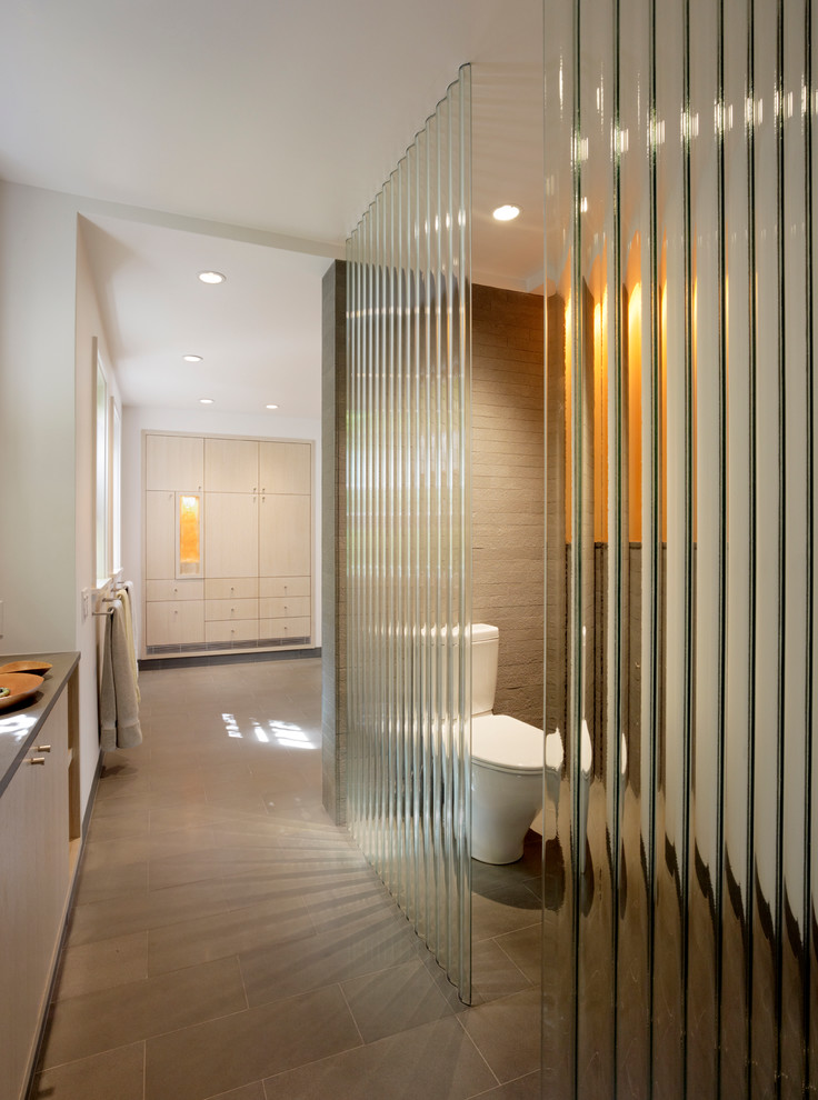 Modern bathroom in San Francisco with flat-panel cabinets, light wood cabinets, a two-piece toilet and beige tile.
