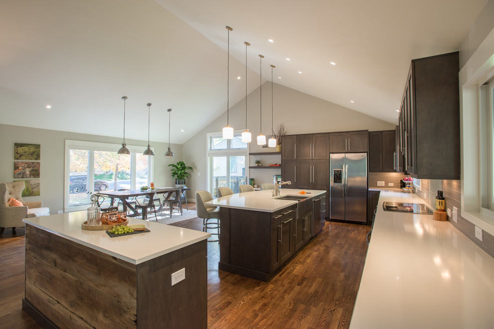 Example of a large transitional l-shaped dark wood floor open concept kitchen design in Denver with a farmhouse sink, shaker cabinets, dark wood cabinets, beige backsplash, stainless steel appliances and two islands