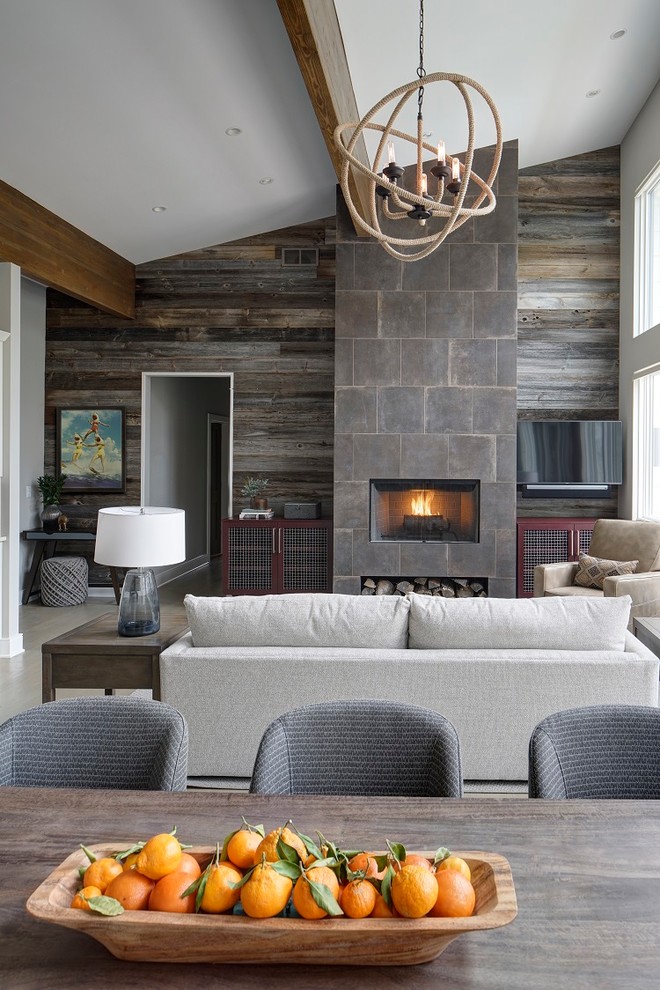 This is an example of a contemporary open concept living room in Chicago with grey walls, a standard fireplace, a tile fireplace surround, a wall-mounted tv and beige floor.