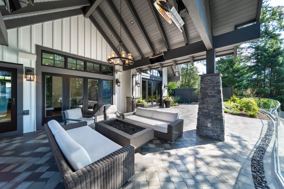 Design ideas for a large country backyard patio in Vancouver with a fire feature, concrete pavers and a roof extension.