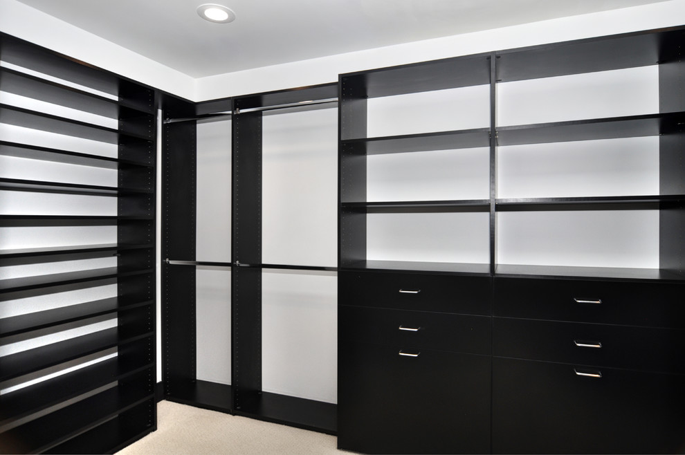 Photo of a large traditional walk-in wardrobe in Orange County with flat-panel cabinets, black cabinets, carpet and beige floor.