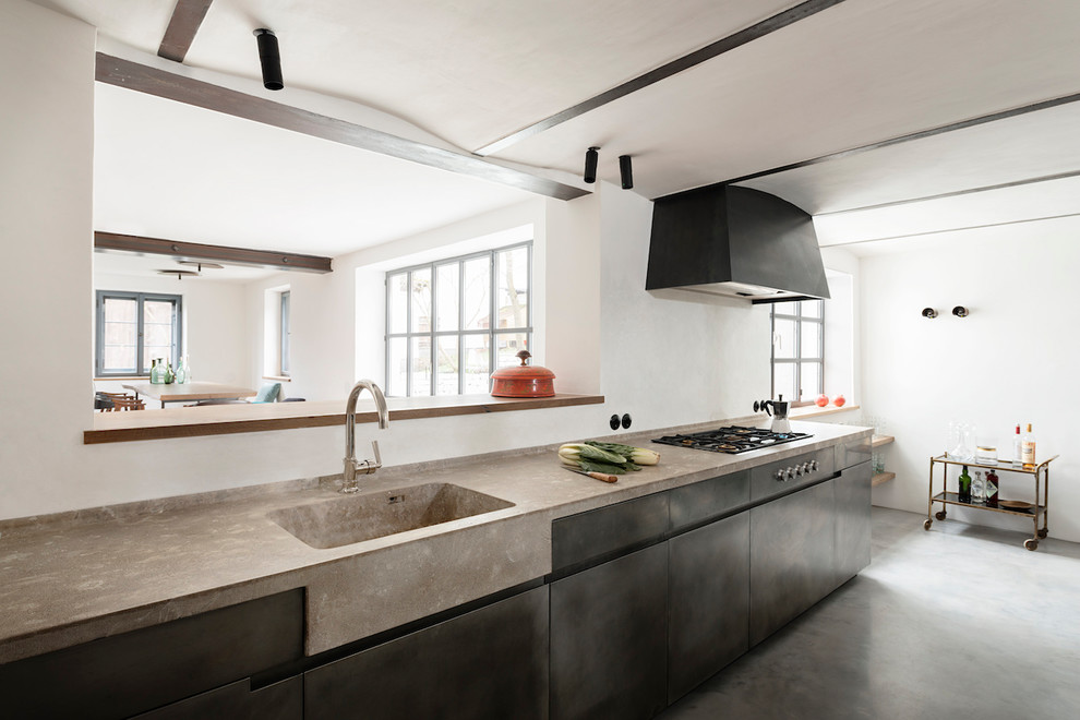 Inspiration for a mid-sized industrial separate kitchen in Munich with an integrated sink, flat-panel cabinets, black cabinets, concrete benchtops, black appliances, concrete floors, no island, grey floor and grey benchtop.