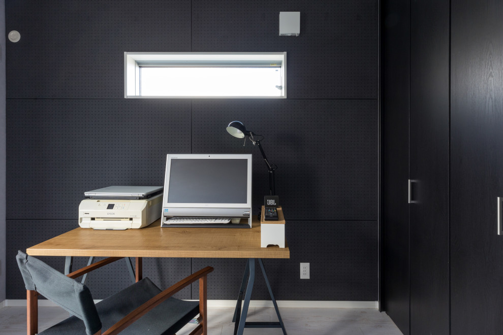 Bild på ett funkis hemmabibliotek, med svarta väggar, vinylgolv, ett fristående skrivbord och grått golv