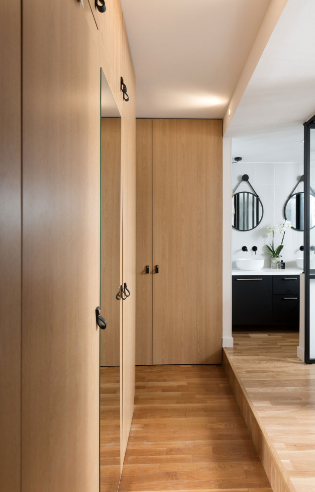 Photo of a large contemporary gender-neutral walk-in wardrobe in Lyon with beaded inset cabinets, light wood cabinets, light hardwood floors and beige floor.
