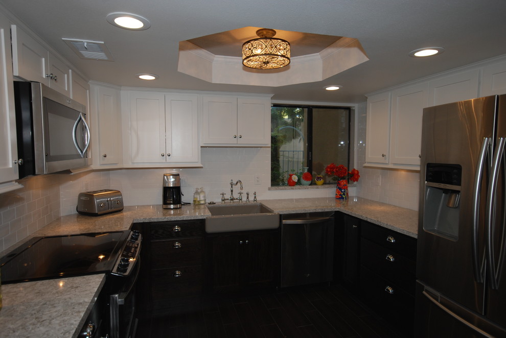 Example of a small transitional u-shaped porcelain tile eat-in kitchen design with a farmhouse sink, shaker cabinets, white cabinets, quartz countertops, white backsplash, subway tile backsplash, stainless steel appliances and gray walls