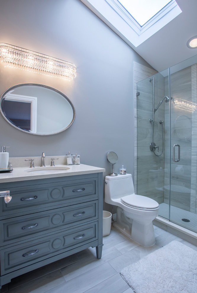 This is an example of a mid-sized contemporary 3/4 bathroom in Miami with raised-panel cabinets, grey cabinets, an alcove shower, a one-piece toilet, gray tile, porcelain tile, grey walls, light hardwood floors, an undermount sink, engineered quartz benchtops, grey floor and a hinged shower door.