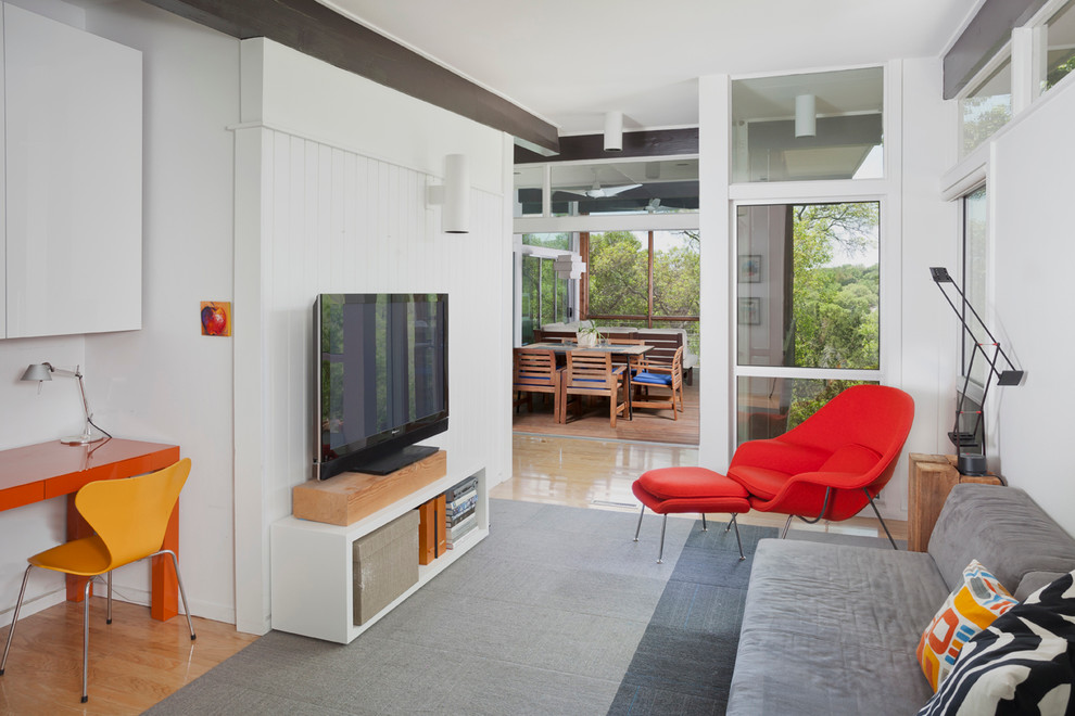 Photo of a small midcentury enclosed family room in Austin with white walls, light hardwood floors and a freestanding tv.