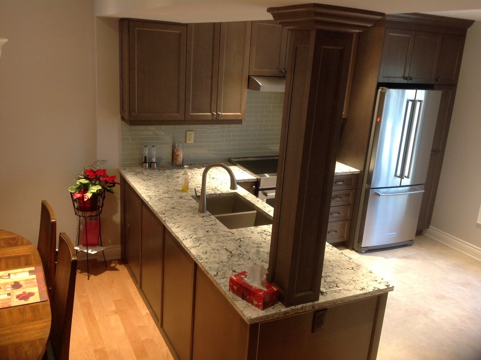 Small transitional l-shaped porcelain tile and beige floor kitchen photo in Toronto with an undermount sink, recessed-panel cabinets, dark wood cabinets, granite countertops, gray backsplash, glass tile backsplash, paneled appliances, no island and multicolored countertops