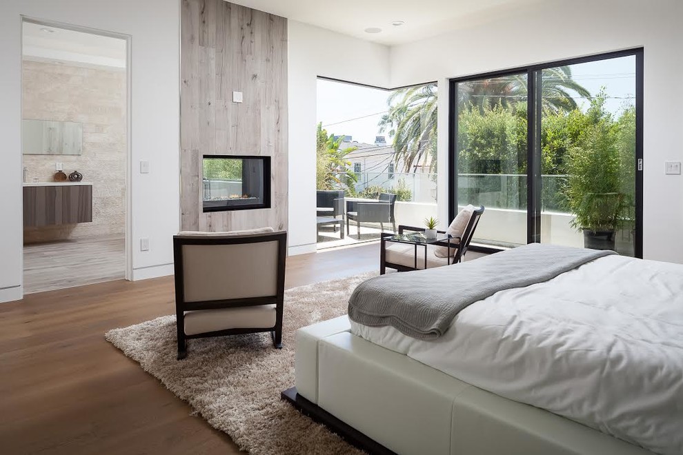 Inspiration for a contemporary master bedroom in Los Angeles with white walls, dark hardwood floors, a two-sided fireplace and a wood fireplace surround.
