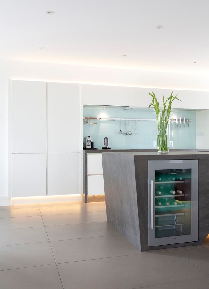 Design ideas for an expansive contemporary u-shaped open plan kitchen with an integrated sink, flat-panel cabinets, white cabinets, engineered stone countertops, green splashback, glass sheet splashback, stainless steel appliances, ceramic flooring and an island.