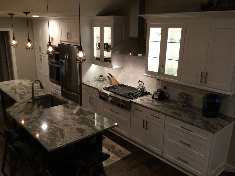 Inspiration for a mid-sized modern galley dark wood floor kitchen remodel with a single-bowl sink, shaker cabinets, white cabinets, quartz countertops, white backsplash, ceramic backsplash, stainless steel appliances and an island