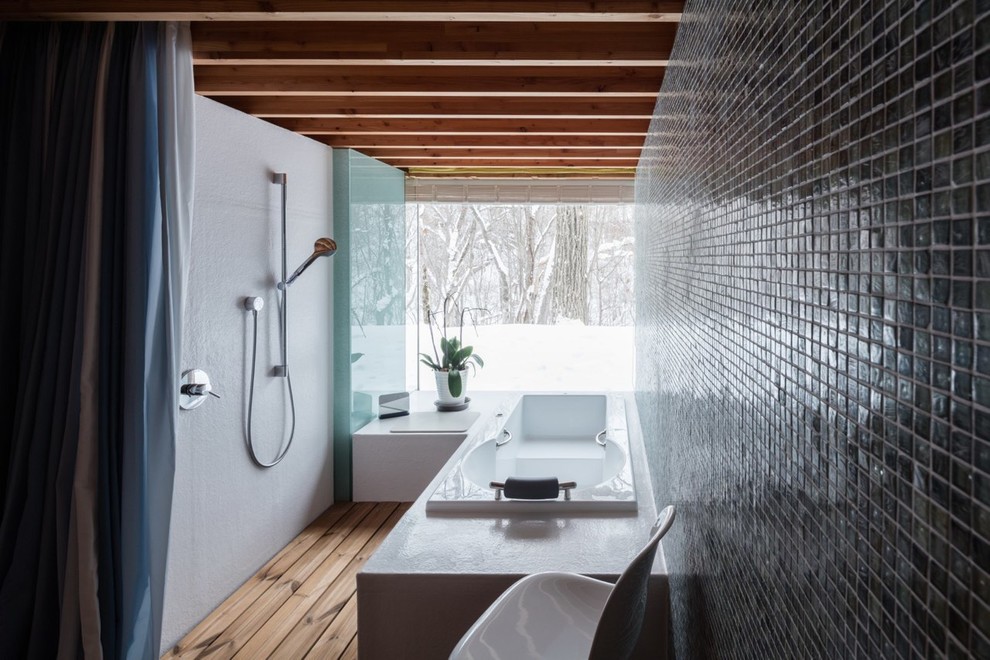 This is an example of an asian master wet room bathroom in Sapporo with a drop-in tub, black walls, light hardwood floors and a shower curtain.
