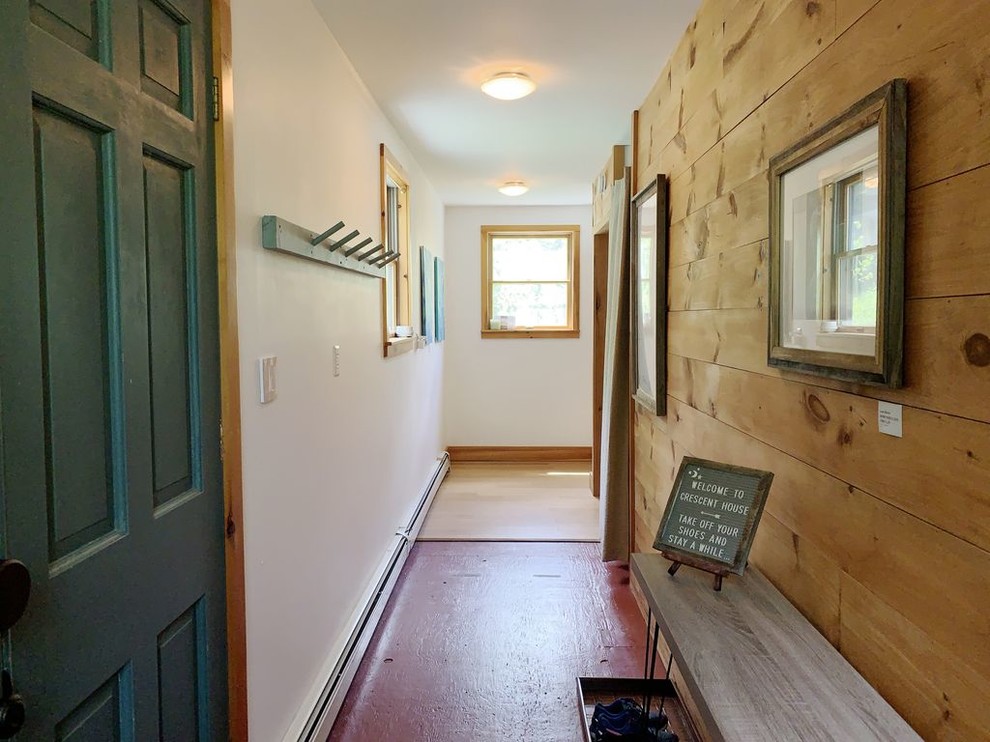 This is an example of an arts and crafts foyer in New York with brown walls, a single front door, a green front door and red floor.