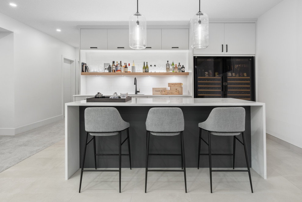 Design ideas for a mid-sized modern galley wet bar in Calgary with an undermount sink, flat-panel cabinets, grey cabinets, quartz benchtops, white splashback, ceramic splashback, porcelain floors, grey floor and white benchtop.