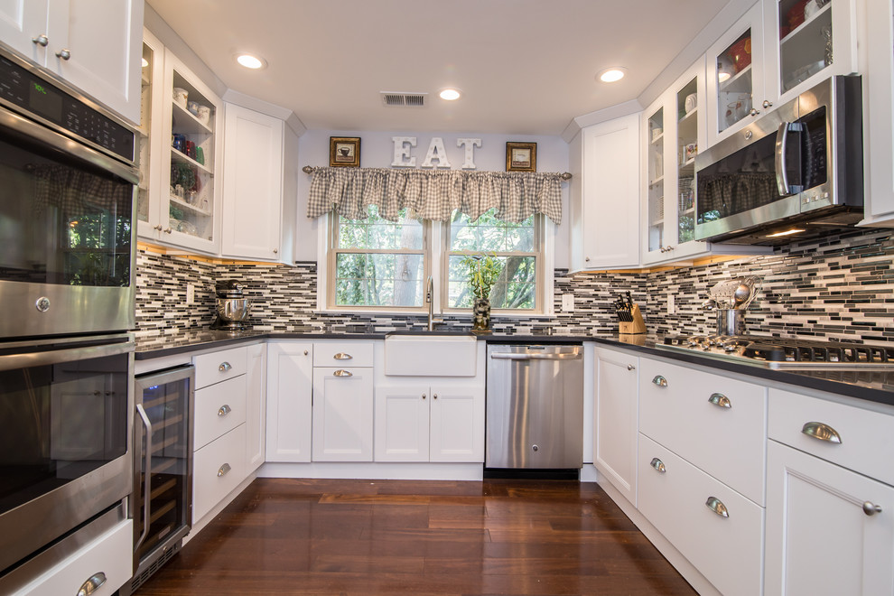 Inspiration for a traditional kitchen in DC Metro with a farmhouse sink, shaker cabinets, white cabinets, stainless steel appliances, dark hardwood floors and brown floor.