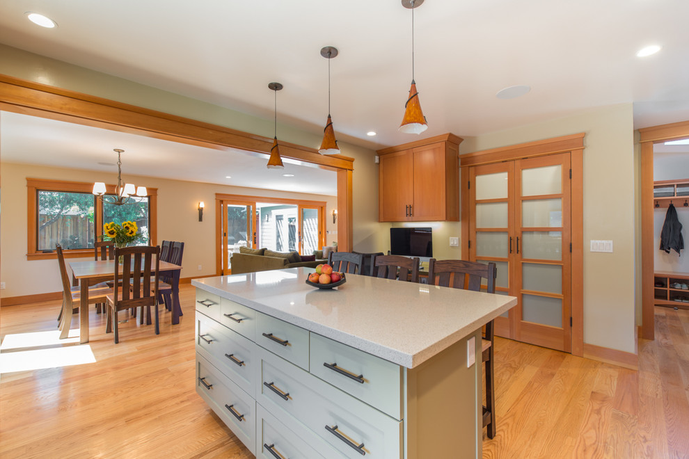 Photo of a large arts and crafts l-shaped separate kitchen in San Francisco with a double-bowl sink, shaker cabinets, light wood cabinets, granite benchtops, beige splashback, ceramic splashback, stainless steel appliances, light hardwood floors, with island and beige floor.