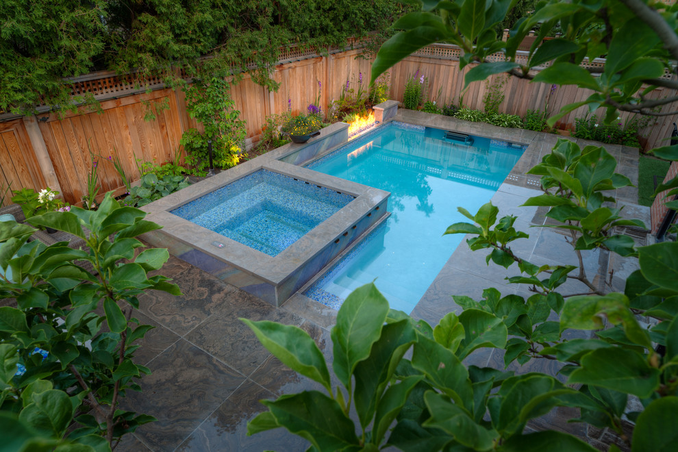 This is an example of a small traditional backyard rectangular lap pool in Other with a water feature and natural stone pavers.
