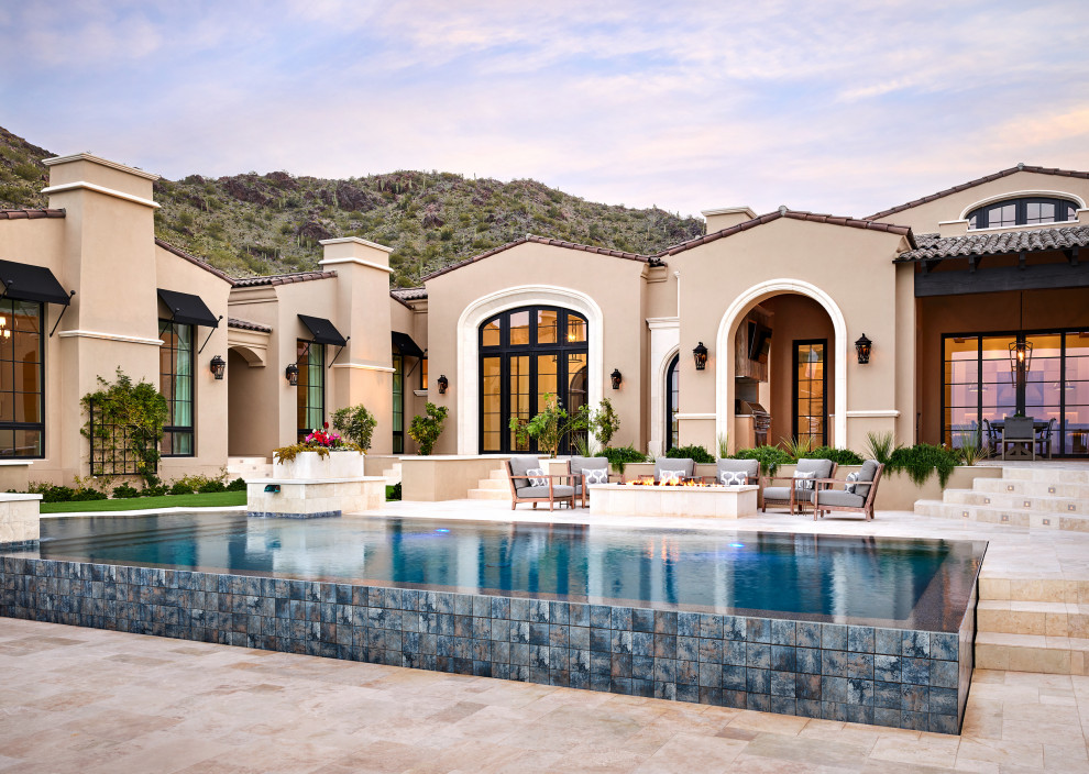 Photo of a large mediterranean backyard rectangular infinity pool in Phoenix with natural stone pavers.