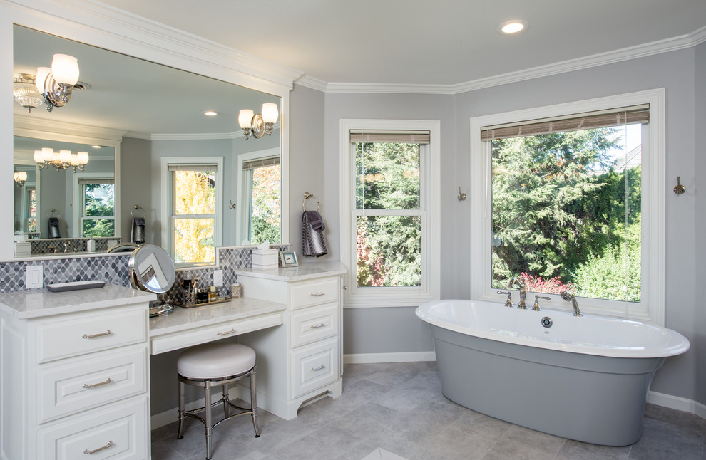 Inspiration for an expansive transitional master bathroom in Portland with furniture-like cabinets, white cabinets, a freestanding tub, a double shower, a two-piece toilet, gray tile, porcelain tile, grey walls, marble floors, an undermount sink, marble benchtops, grey floor, a hinged shower door and grey benchtops.