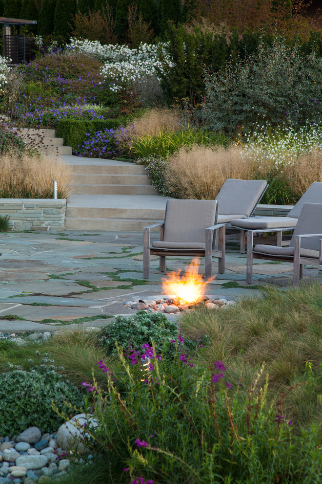 Inspiration for a beach style sloped full sun garden for summer in Seattle with a fire feature and natural stone pavers.
