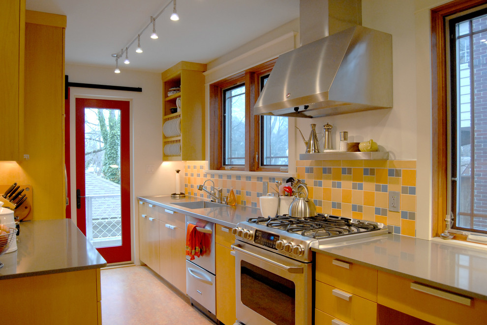 This is an example of a contemporary galley separate kitchen in Other with an integrated sink, stainless steel appliances, open cabinets, yellow cabinets and yellow splashback.