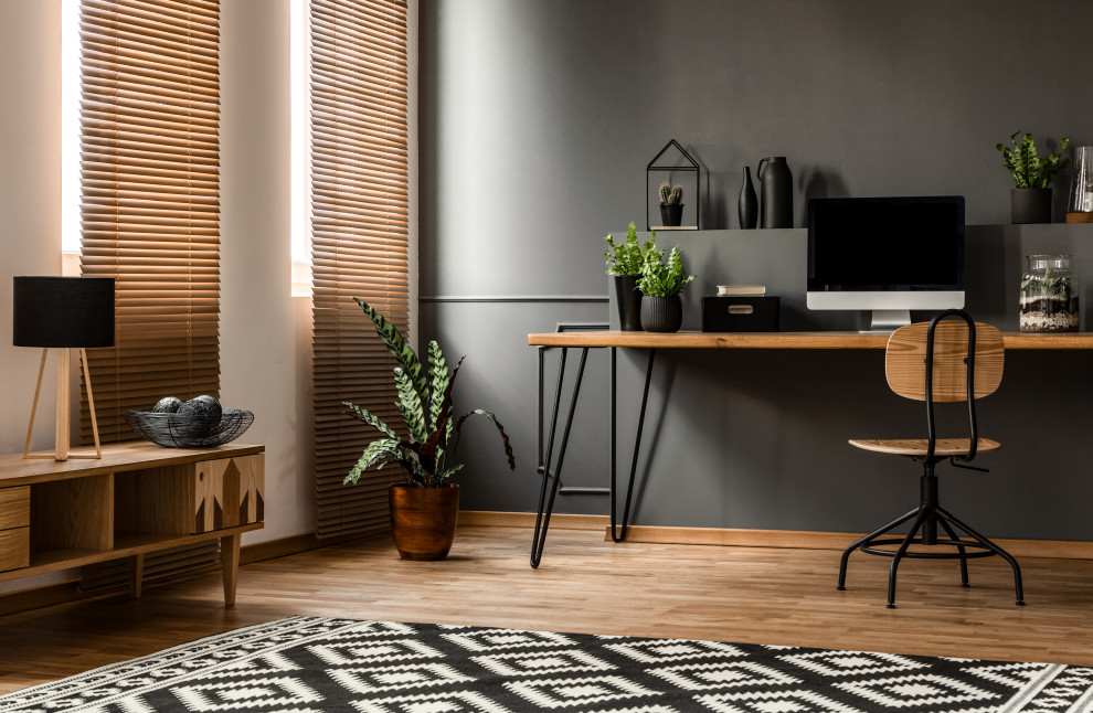 Modelo de despacho retro con paredes negras, suelo de madera en tonos medios y escritorio independiente